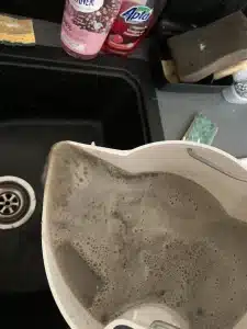 le bac de vidange contenant l'eau sale apres une intervention de nettoyage de canapés par pg solutions